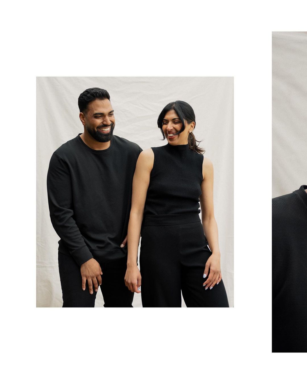 Portrait of a smiling East Indian couple in black tops and pants against a cream-colored muslin backdrop, shot in a bright photo studio.