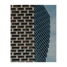 Close-up architectural view of a modern skyscraper facade with repeating balcony patterns and glass windows against a clear sky