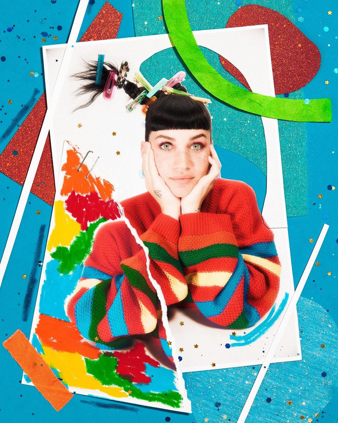 Collage portrait of a young woman with a playful expression, wearing a colorful sweater against a vibrant blue and patterned background.
