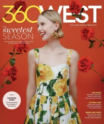 Magazine cover featuring a smiling blonde woman wearing a yellow floral print dress against a solid orange background with floating red roses.