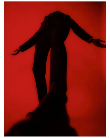Full body photo of a person in a dark suit posing with arms outstretched on a red background. Fashion and posing concept.