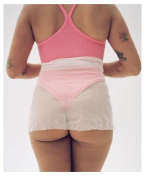 Rear view of a person wearing a pink athletic tank top and sheer white shorts against a clean white seamless studio background.