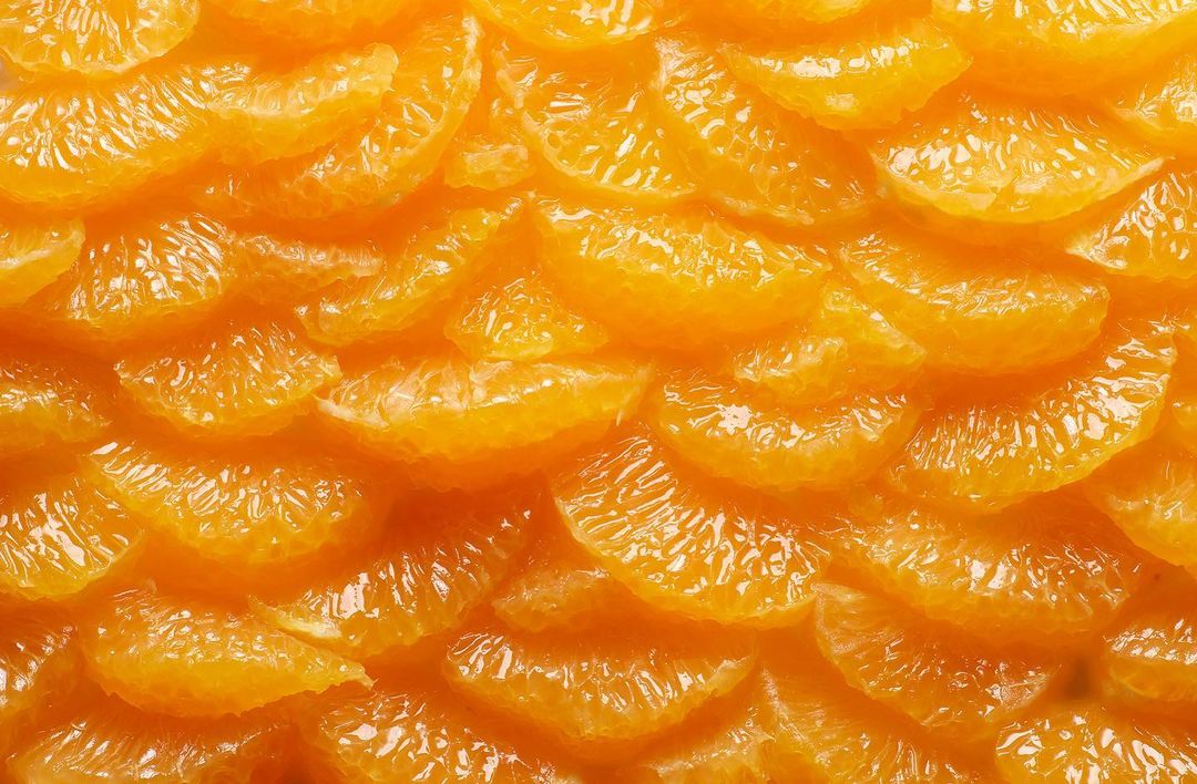 Close-up shot of a vibrant orange texture formed by overlapping citrus segments, creating an abstract pattern.