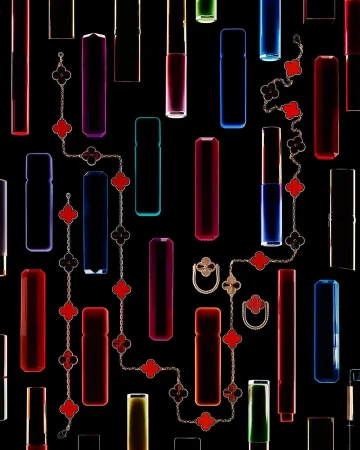 Luxe still life: Assorted colorful lipstick tubes and fine jewelry on a black backdrop creating a graphic product shot.