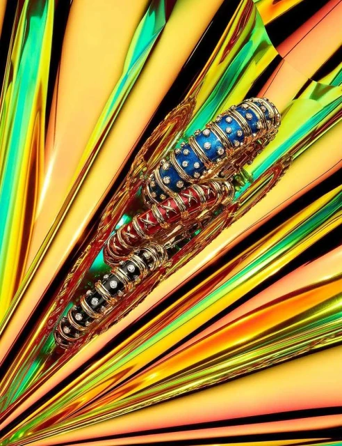 Elevated product shot of a jeweled bangle in black, red, and blue with gold inlay against a backdrop of dynamic yellow and green stripes.
