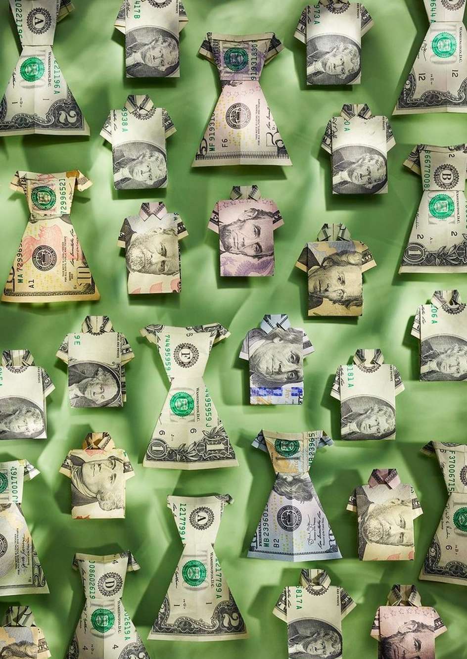 Arrangement of folded US dollar bills shaped as dresses and shirts on a green background. Creative money and finance concept.