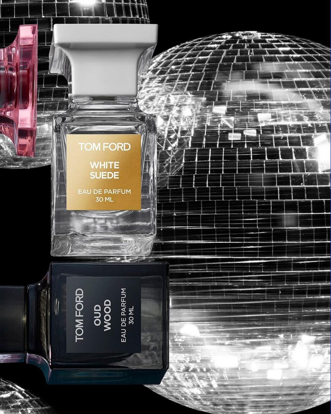 Tom Ford Oud Wood and White Suede perfume bottles with disco balls on black background, beauty and cosmetics product photography.