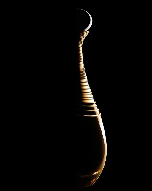 Elegant, curved perfume bottle against a stark black background, softly lit to highlight its shape and the moon shape at the top.
