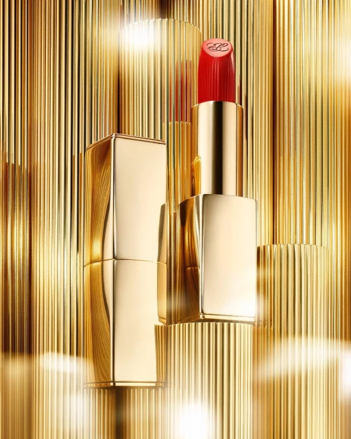 Close-up product shot of red lipstick in gold component with a gold corrugated surface background in a vertical orientation.
