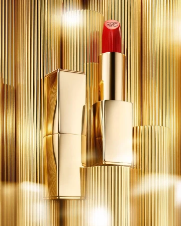 Close-up product shot of red lipstick in gold component with a gold corrugated surface background in a vertical orientation.