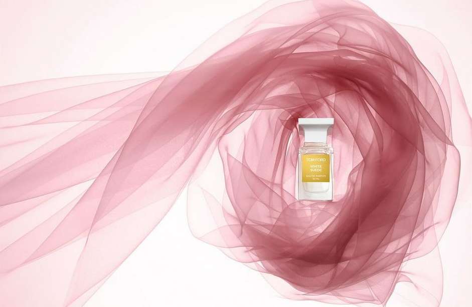 Tom Ford White Suede perfume bottle on a white surface with a soft, flowing sheer pink fabric. Studio shot, beauty product photography.