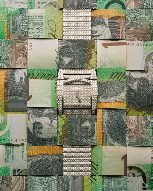 A creative still life features a diamond watch on a woven background of Australian one hundred dollar bills, highlighting luxury and finance.