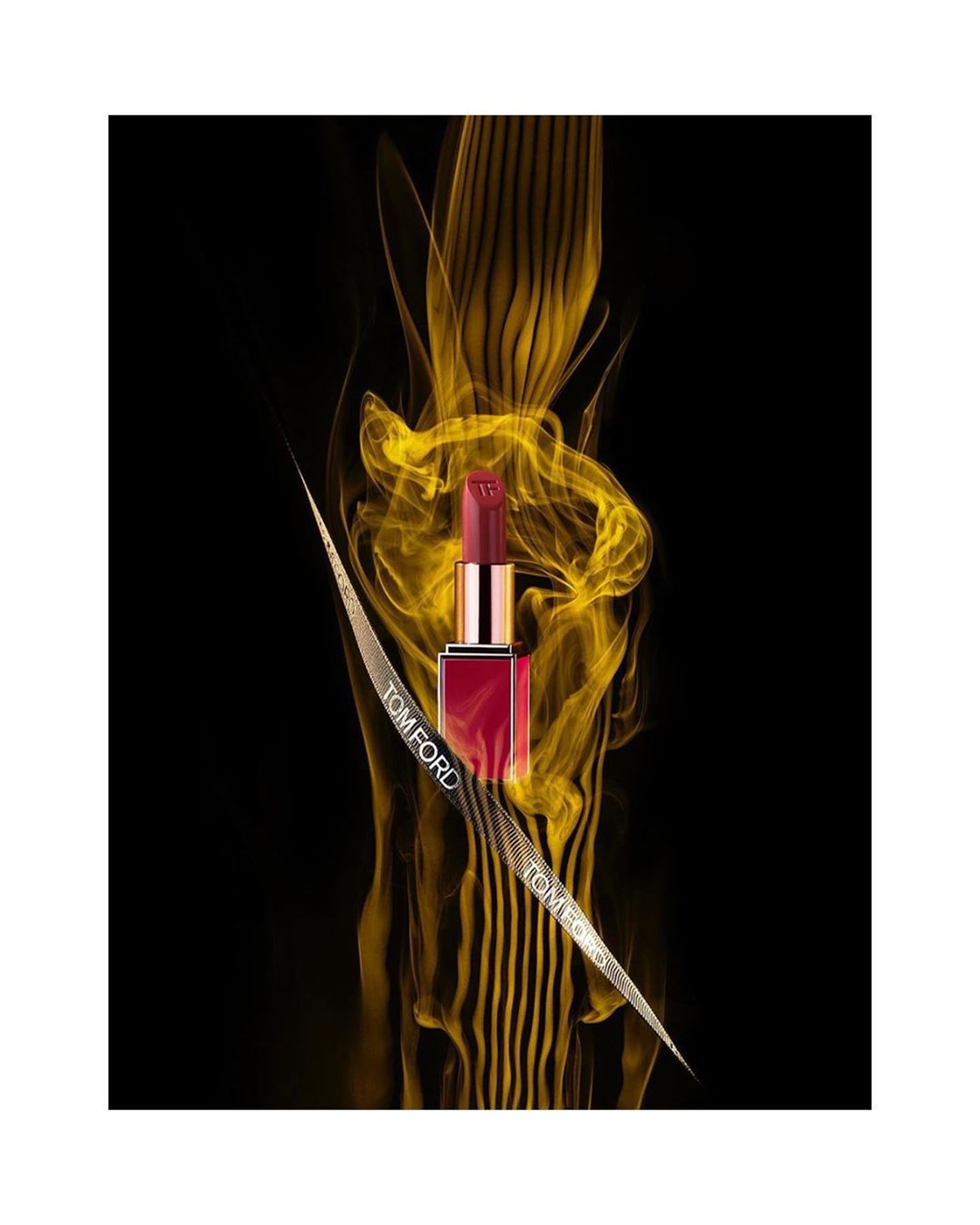Tom Ford lipstick stands against a backdrop of dynamic golden light trails, creating a striking beauty advertisement with luxury appeal.