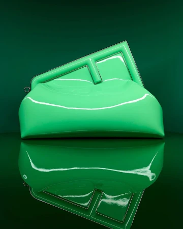 Stylish glossy green clutch purse with geometric frame and handle, reflecting against a glossy dark-green backdrop, studio lighting.