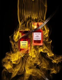 Tom Ford Lost Cherry and Jasmin Rouge perfume bottles surrounded by golden smoke against a black background