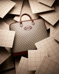 Monogram briefcase surrounded by scattered grid-patterned tiles photographed by Mitchell Feinberg