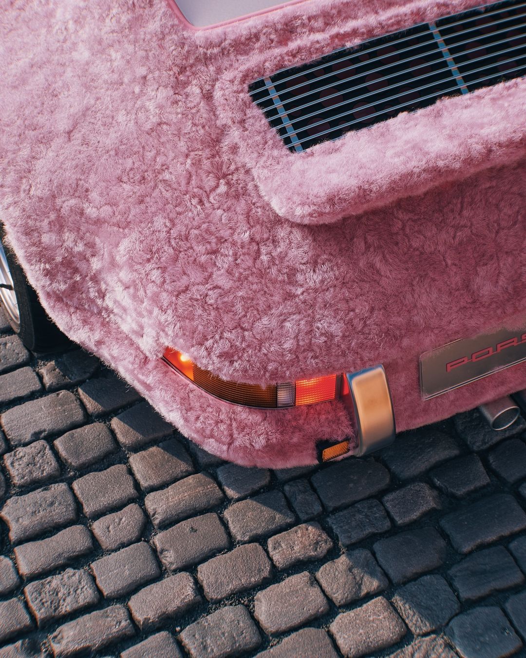 Close-up of a vintage pink Porsche covered in fur parked on a cobblestone street, showcasing its unique exterior and vintage style.