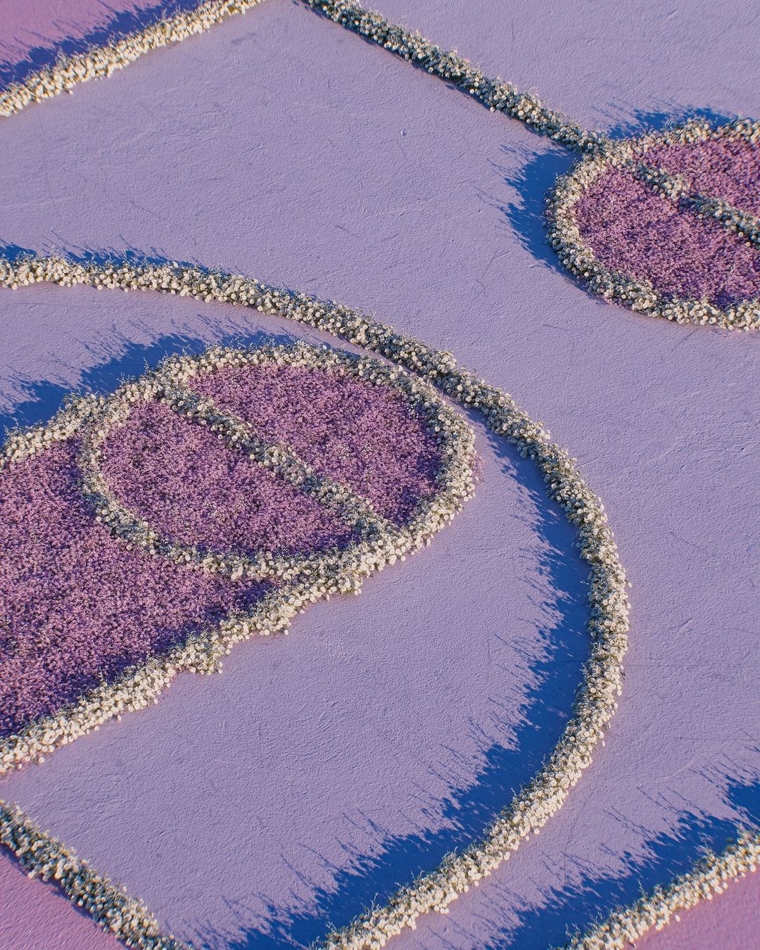 Abstract flat lay of a textured light purple surface featuring raised designs in the shape of musical notes and round shapes.