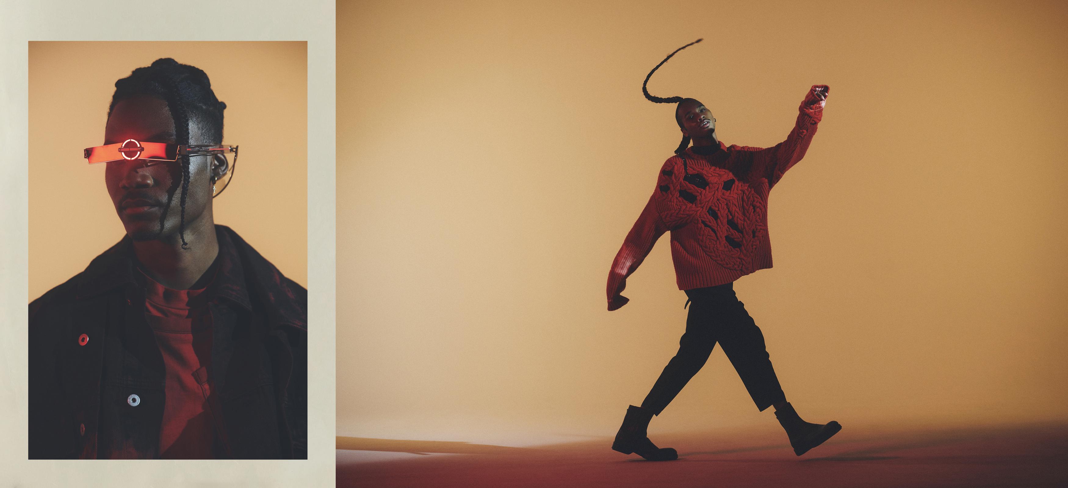 A fashionable Black male model wears a red sweater and cyberpunk glasses in a studio fashion shot with a warm color palette.