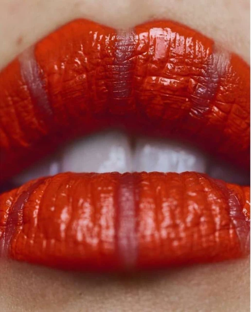 Macro shot of red lipstick with vertical clear stripes on an adult female. Close-up on the face with lips as a focal point.