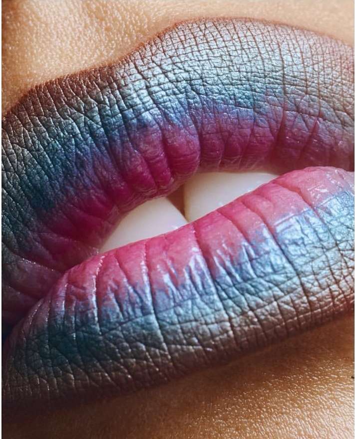 Close-up of a woman's lips with textured and multi-colored lipstick, showcasing details of the makeup and lip texture.