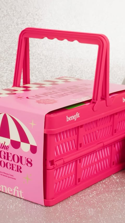 Bright pink Benefit Cosmetics gift set in a picnic basket-style container with packaging and festive glitter background, product shot.