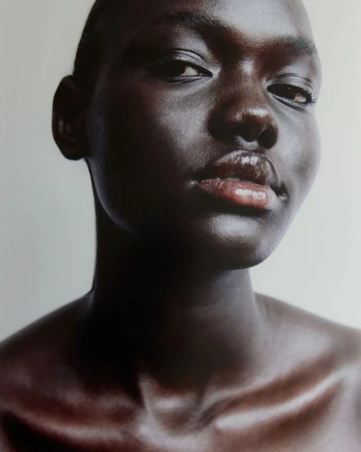 Close-up portrait of a young Black female adult with smooth skin, featuring eye-level angle and studio lighting on a neutral backdrop.