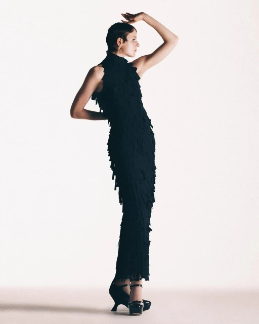 Fashion shot: Woman in an elegant black dress strikes a pose against a bright white backdrop, highlighted by eye-catching platform heels.