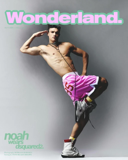 Magazine cover featuring a shirtless male model in pink shorts, posing in front of a gray background. He is wearing high top sneakers.