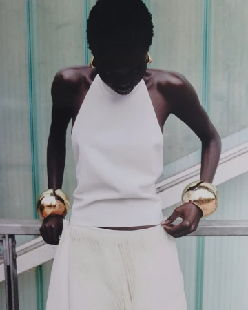 Black woman wearing white halter top and oversized gold cuffs by photographer Morgan Roberts