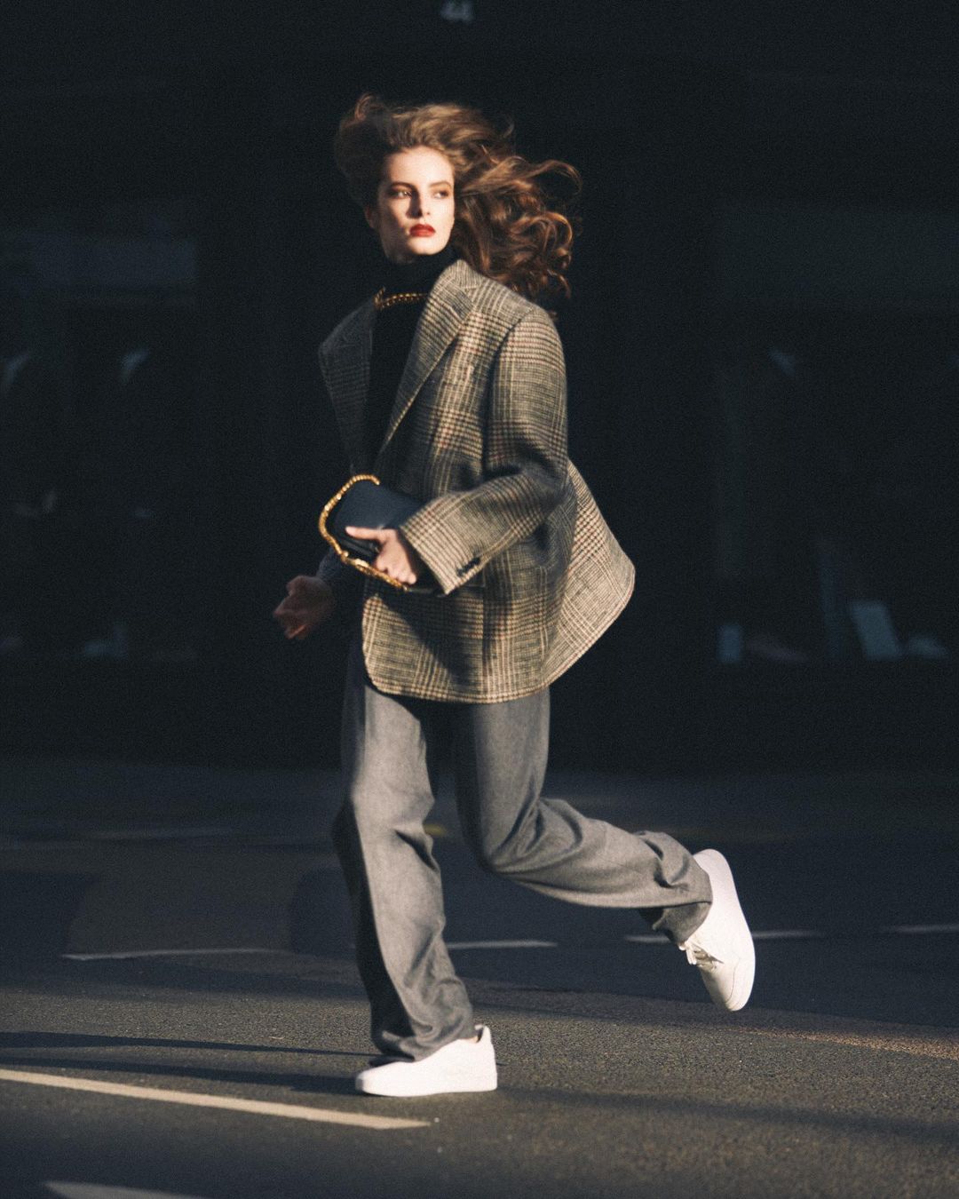 Model in plaid blazer and grey trousers running outdoors in London, captured by Morgan Roberts
