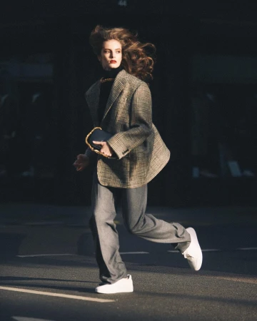 Model in plaid blazer and grey trousers running outdoors in London, captured by Morgan Roberts