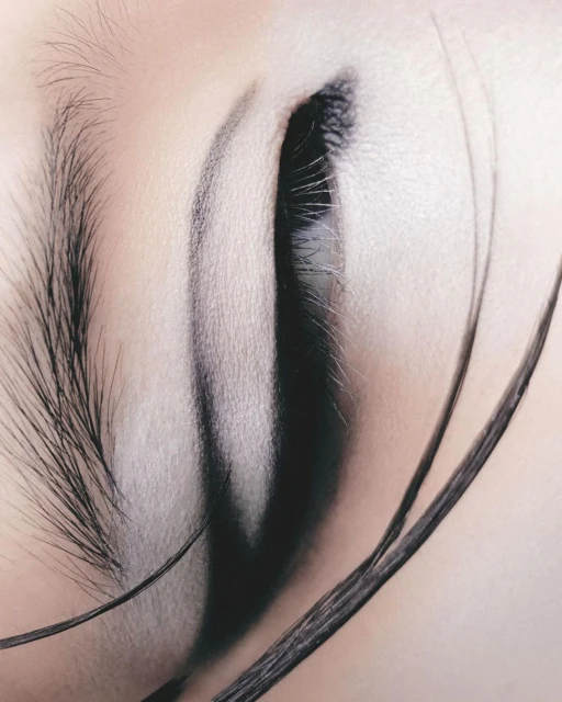 Close-up photograph of an adult female eye featuring long eyelashes and defined brow, set against a soft, neutral-toned skin.