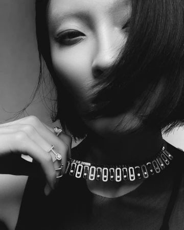Close-up black and white portrait of a model wearing a diamond choker necklace and rings, photographed in London.