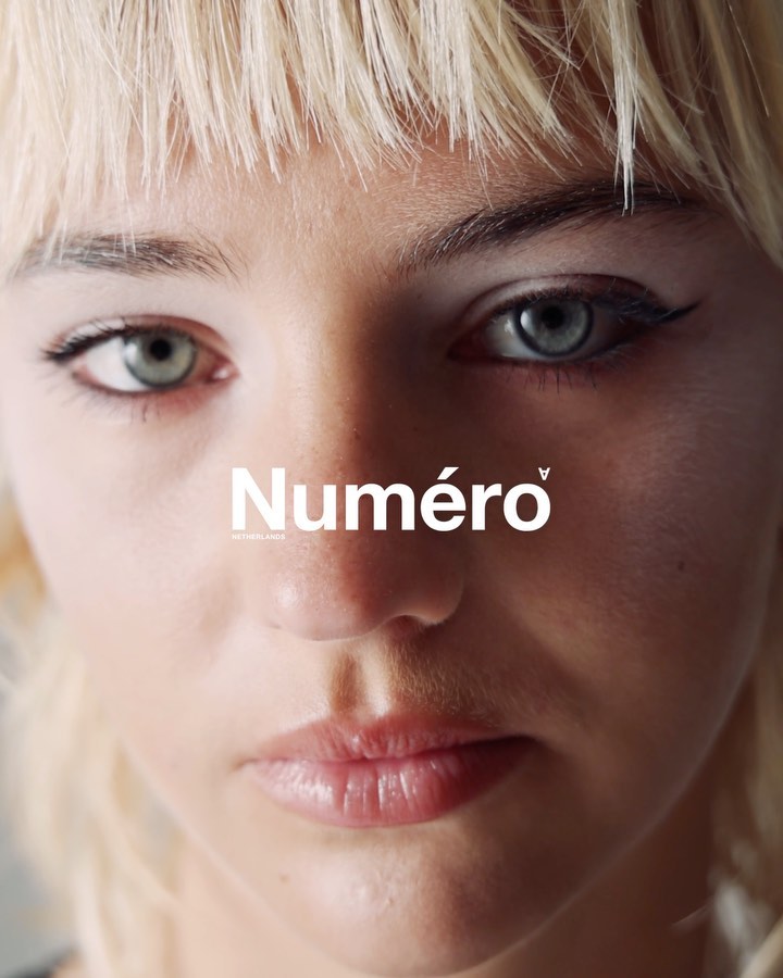 Close-up portrait of a blonde adult woman with blue eyes and winged eyeliner, featuring the brand logo of Numéro magazine.