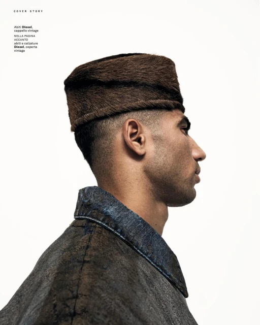Profile shot of a man wearing a fur cap, with a simple white background and wearing a jacket with dark denim collar.