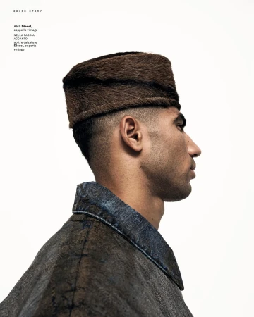 Profile shot of a man wearing a fur cap, with a simple white background and wearing a jacket with dark denim collar.