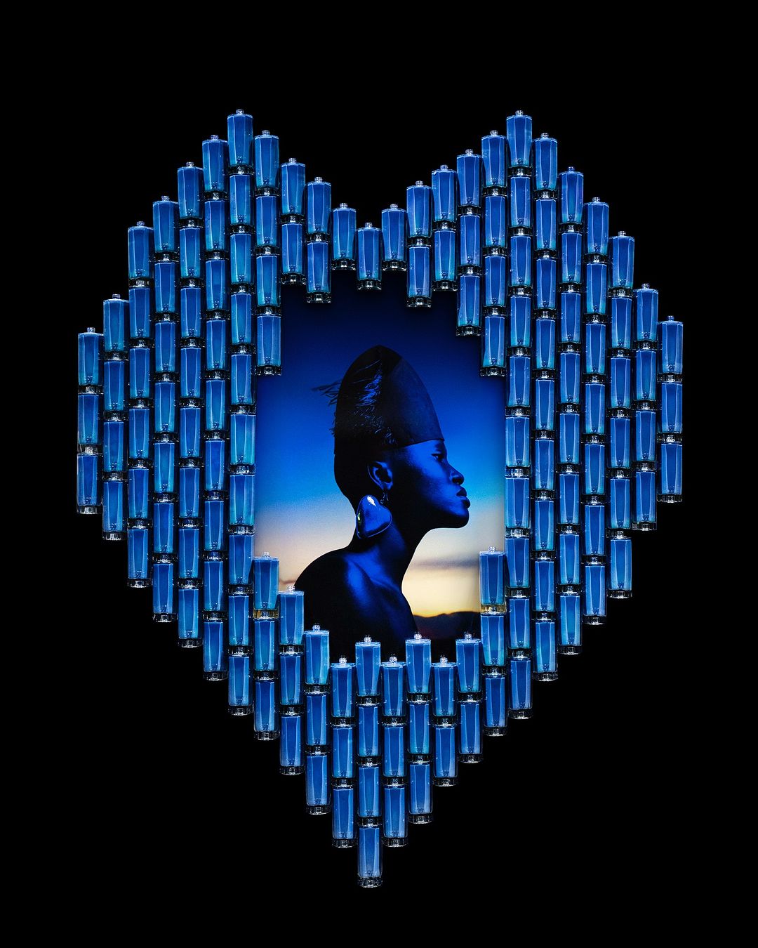 Artistic portrait of African woman framed by heart-shaped batteries on a black background with blue hues and an ethereal atmosphere.