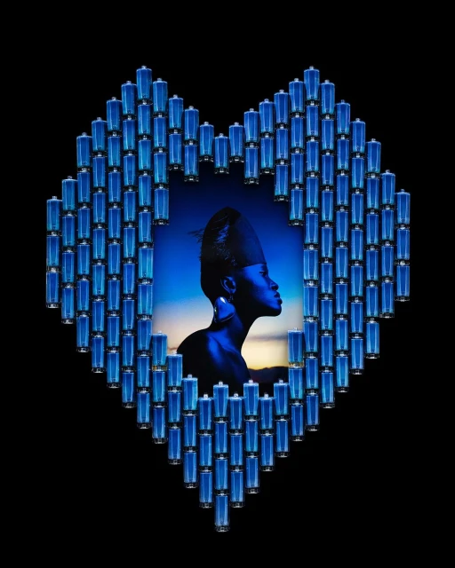 Artistic portrait of African woman framed by heart-shaped batteries on a black background with blue hues and an ethereal atmosphere.