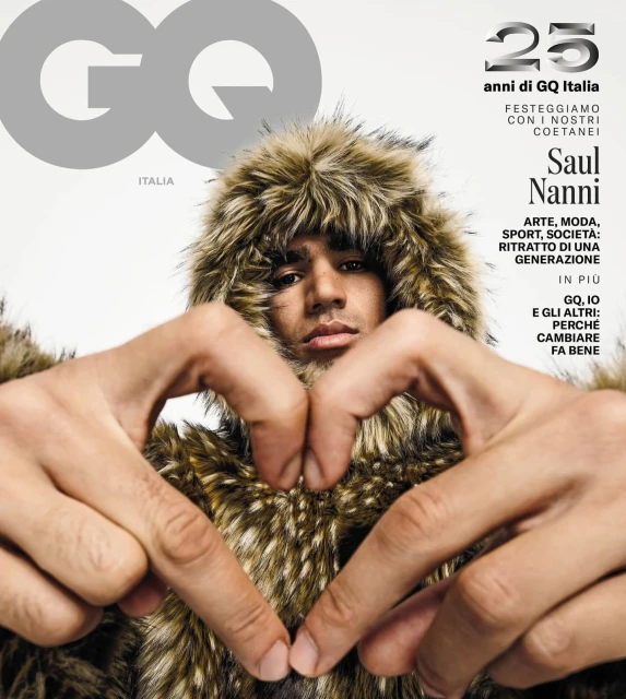 GQ Italia cover featuring Saul Nanni with a fur hood and making a heart shape with his hands against a white background.