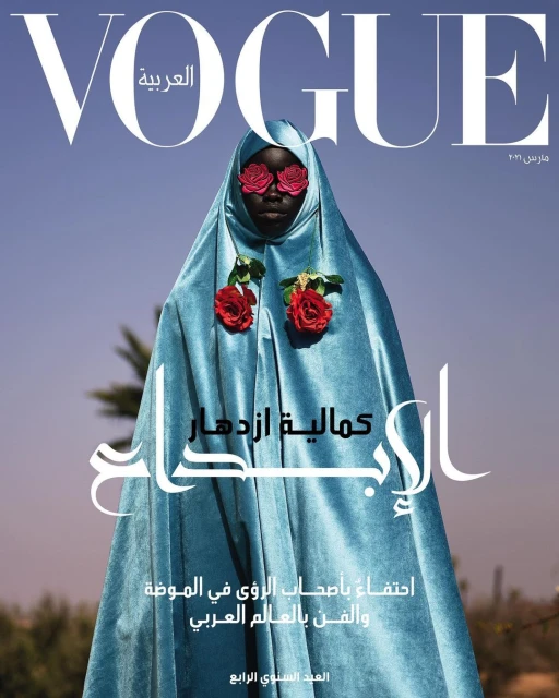Vogue Arabia cover featuring a Black woman in a light blue robe adorned with red roses, set against a clear blue sky backdrop.