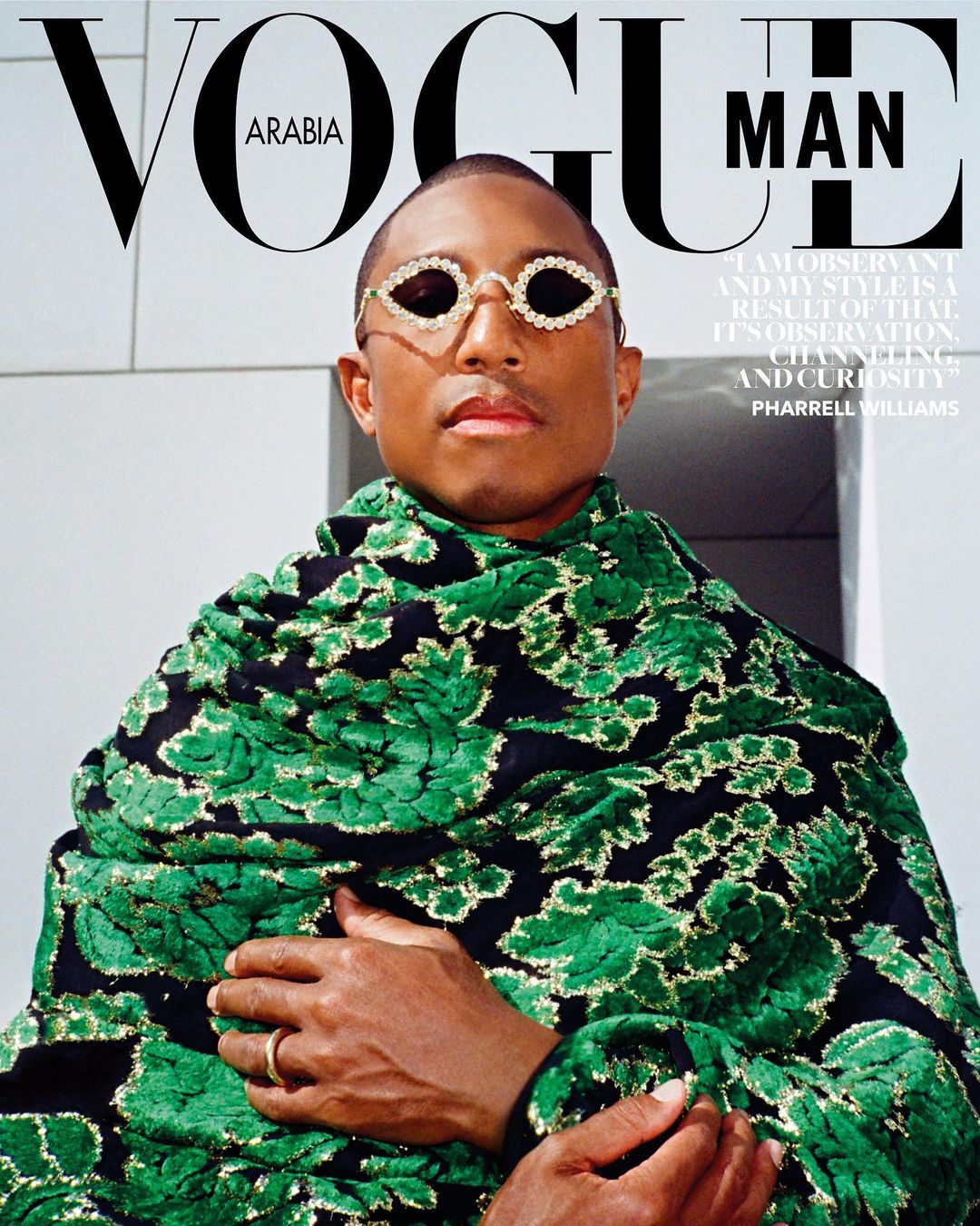 Magazine cover featuring Pharrell Williams wearing embellished sunglasses and a green floral patterned wrap. Vogue Man Arabia.