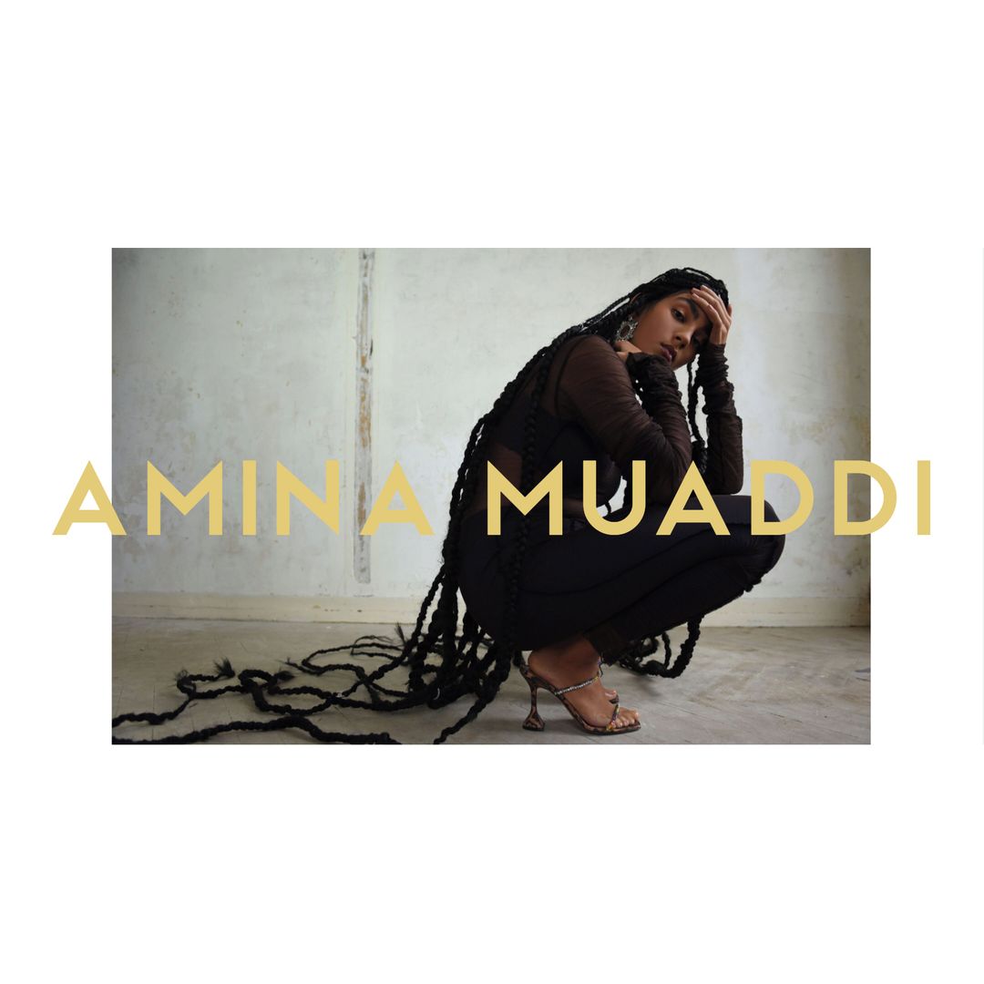 Woman in a crouched pose wearing a dark outfit and high heels, long braids, looking down with a cream-colored wall background and text overlay.
