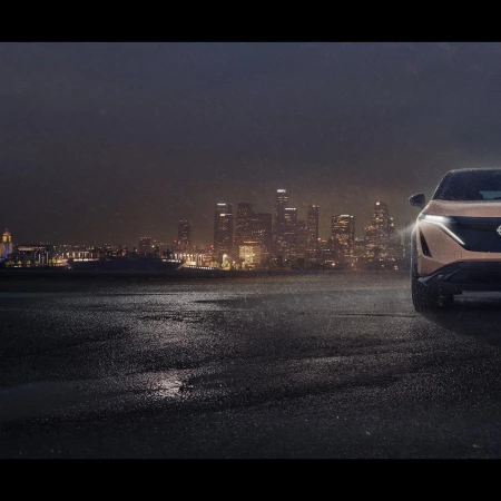 Bronze Nissan Ariya electric SUV parked in an urban setting against a backdrop of a lit-up city skyline at night.