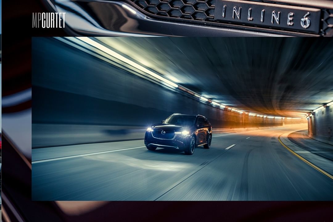 A sleek black SUV with headlights on drives through a brightly lit tunnel, creating a dramatic effect with tunnel lights.