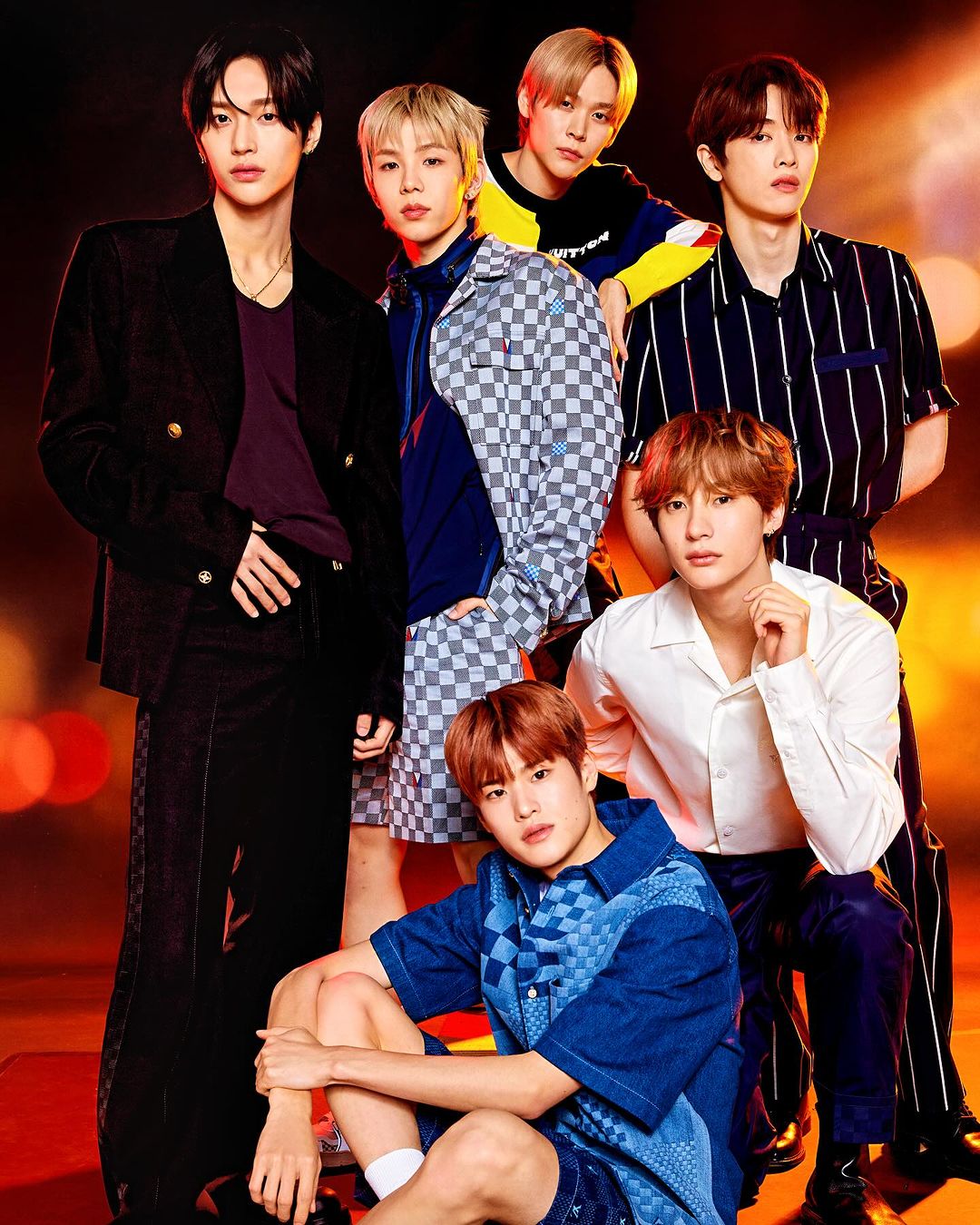 Group studio shot of seven young adult Asian male singers and performers in casual fashion against a blurred bokeh background.