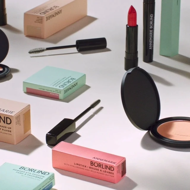 Cosmetics display featuring Annemarie Börlind lipstick, mascara, and face powder in studio lighting. Beauty and makeup concept.
