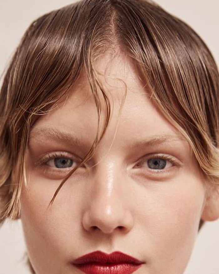 Close-up beauty portrait of a woman with wet-look hair and bold red lipstick photographed in Paris.