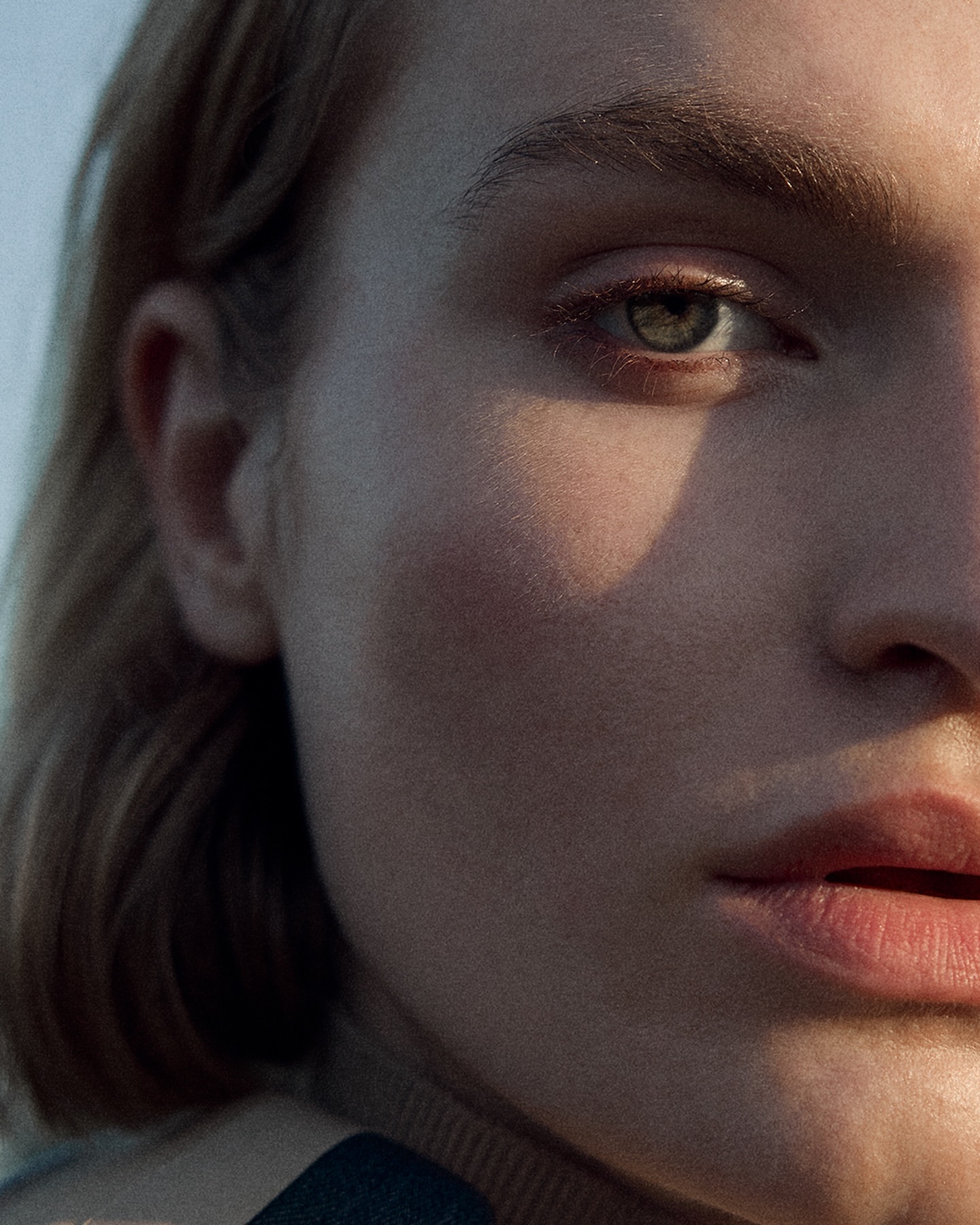 Close-up portrait of a fair-skinned adult female with short blonde hair, dramatic lighting, and neutral expression in a studio setting.