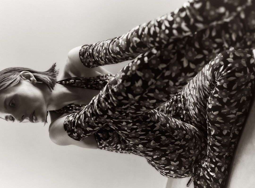 Low-angle shot of a young woman in a floral-patterned jumpsuit, lying down and looking to the side, showcasing a unique perspective.